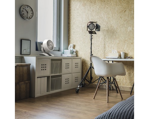 Un bureau avec un bureau, une étagère et un ventilateur