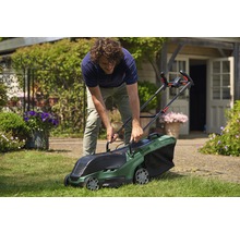 Un homme utilise une tondeuse à gazon Bosch dans le jardin.