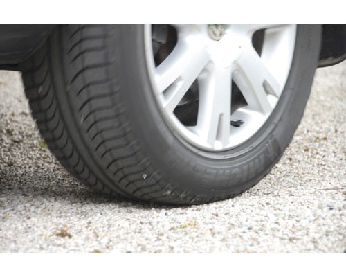 Une roue de voiture avec un pneu sur du gravier