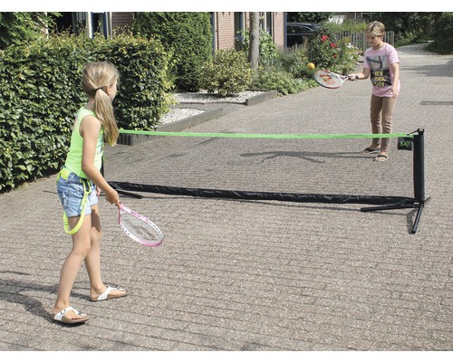 Deux enfants jouent avec un filet de tennis portable à l''extérieur.