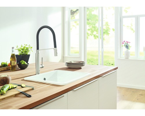 Évier de cuisine avec robinet sur un plan de travail avec des aliments dans une cuisine lumineuse.