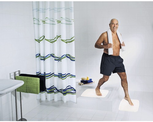 Salle de bain lumineuse avec rideau de douche, porte-serviettes, tapis de bain et une personne avec une serviette