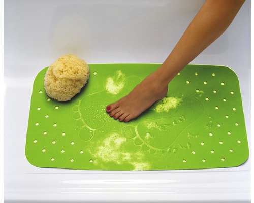 Tapis de bain vert avec empreintes de pieds et éponge dans la baignoire