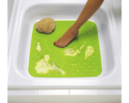 Tapis de bain vert avec empreinte de pied et éponge de bain dans une baignoire blanche.