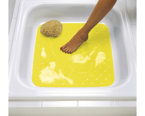 Tapis de bain jaune avec pied dans une baignoire blanche