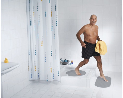 Salle de bains avec rideau de douche et tapis de bain, une personne sortant de la douche