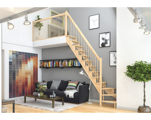 Salon avec escalier en bois menant à la mezzanine, bibliothèque et canapé.