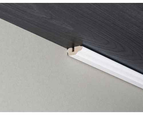 Plinthe arrondie blanche entre le mur et le sol stratifié foncé