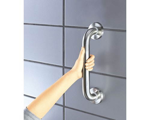 Une main tient une barre d''appui sur un mur carrelé pour plus de sécurité dans la salle de bains.