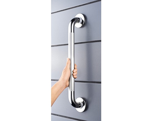 Person hält einen silberfarbenen Haltegriff an einer Wand