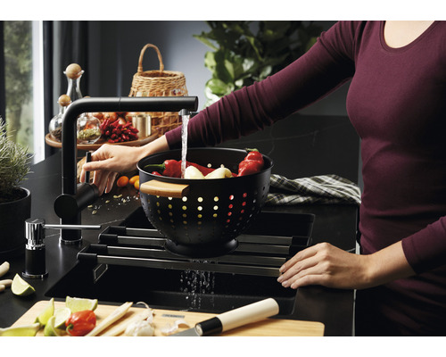 Évier avec égouttoir, robinetterie et femme lavant des légumes