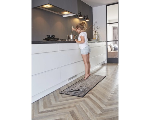 Cuisine avec tapis de cuisine imitation bois et jeune fille près du fourneau
