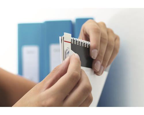 Hände entfernen einen Aufkleber von einem Notizbuch.