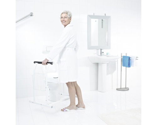 Helles Badezimmer mit Toilette, Waschbecken, Spiegel, Handtuchhalter und Toilettenstützgestell zur Unterstützung