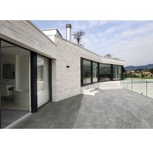 Extérieur d''une maison avec sol en pierre, terrasse et garde-corps en verre