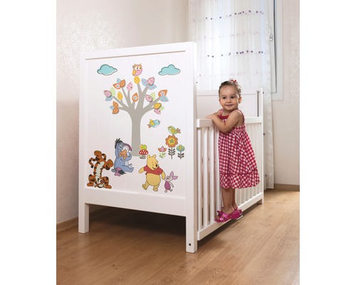 Weißes Kinderbett mit Winnie Puuh Motiven in einem Kinderzimmer.