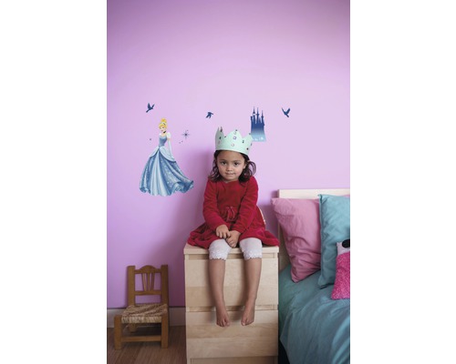 Mädchen mit Krone sitzt vor Wand mit Cinderella Wandtattoo im Kinderzimmer