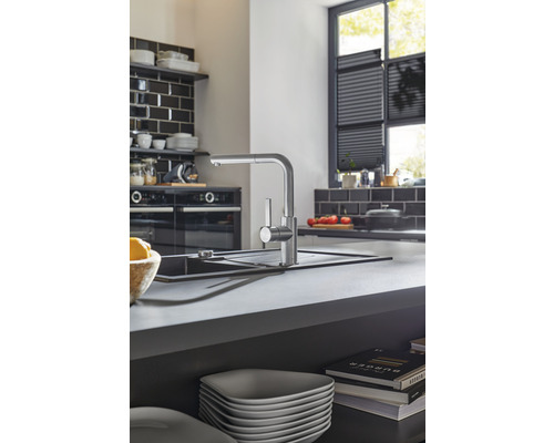 Küchenszene mit Spültischarmatur, Spüle und Küchenutensilien auf einer Arbeitsplatte.