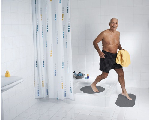 Salle de bain lumineuse avec rideau de douche, tapis de bain et une personne avec une serviette