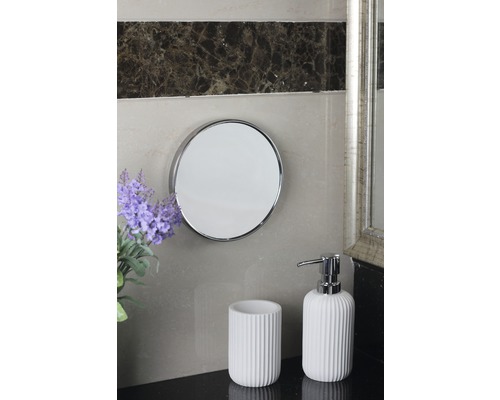 Scène de salle de bain avec miroir rond, gobelet à brosse à dents et distributeur de savon