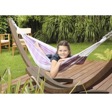 Fille se détend dans un hamac rayé avec structure en bois dans le jardin