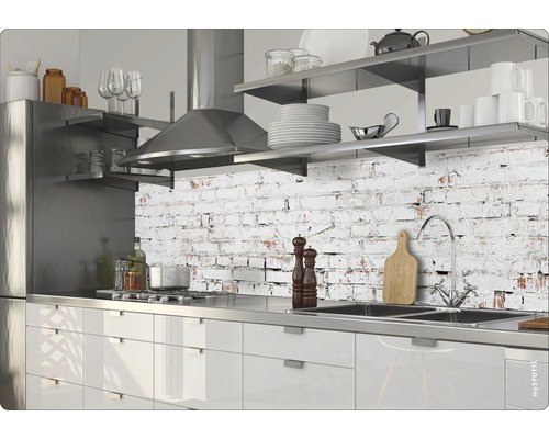 Moderne Küche mit Edelstahlgeräten und Arbeitsplatte vor einer Wand mit Backsteinmuster