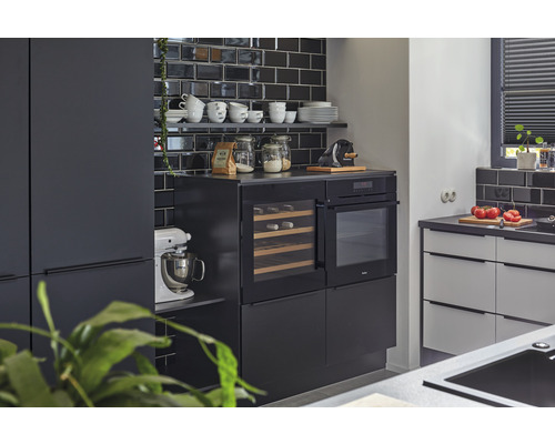 Cuisine moderne avec carrelage noir, appareils intégrés et ustensiles de cuisine sur des étagères.