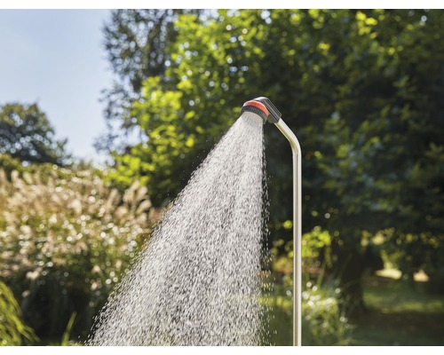 Gartendusche mit laufendem Wasser vor grüner Vegetation
