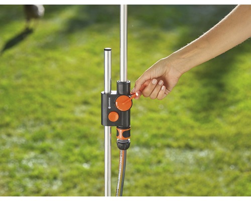 Eine Hand bedient einen Wasserverteiler am Wasserhahn im Garten.