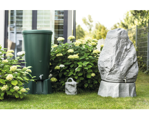 Gartenszene mit einem grünen und einem grauen Regenspeicher in Steinoptik sowie einer Giesskanne