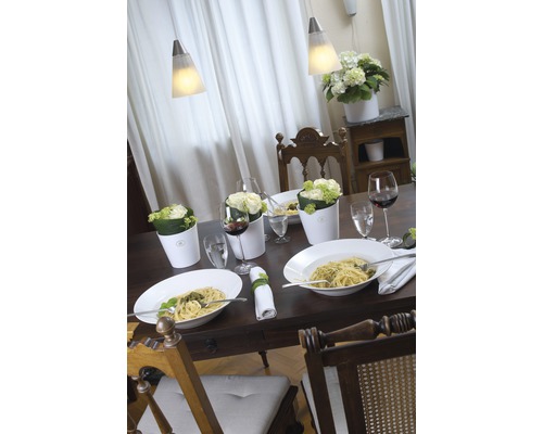 Gedeckter Esstisch mit Pasta, Getränken, Blumen und Lampen