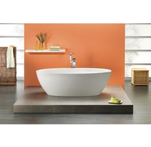 Freistehende Badewanne in einem hellen Badezimmer mit gefliestem Podest und Ablagefläche