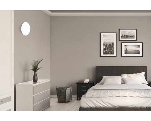 Schlafzimmer mit Bett, Kommode, Nachttisch, Wandleuchte und Bildern