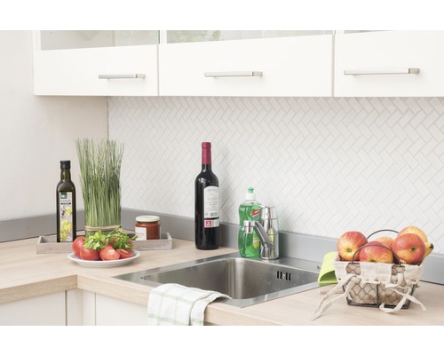 Küchenszene mit Spüle, Armatur und verschiedenen Küchenutensilien auf der Arbeitsplatte.