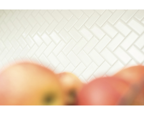 Weisse Fliesenwand im Fischgrätmuster