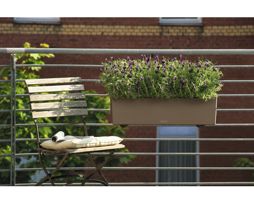 Scène avec une jardinière avec des plantes suspendue à une balustrade et une chaise pliante avec coussin et magazine