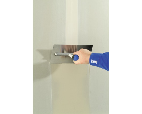 Knauf Fugenfüller Leicht Spezialgips 5 kg Eine Person glättet eine Wand mit einer Glättkelle und Spachtelmasse.