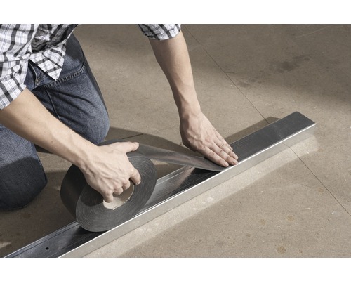 Eine Person befestigt Dichtungsband an einem Metallprofil.