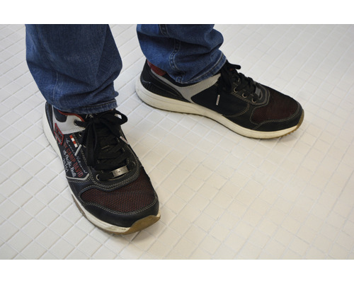 Ein Paar Schnürschuhe aus Textil und Synthetik am Fuß einer Person.