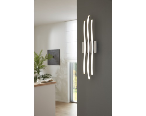 Applique murale moderne avec trois éléments lumineux incurvés sur un mur gris