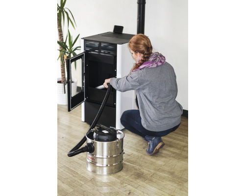 Frau reinigt Kaminofen mit Aschesauger