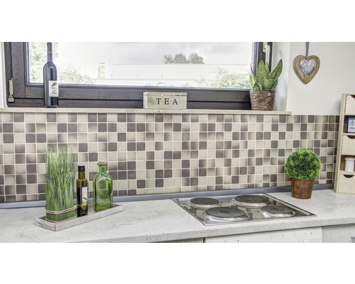 Scène de cuisine avec carrelage mosaïque, plaque de cuisson et éléments décoratifs.