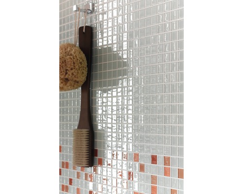 Gros plan d''un mur avec des carreaux de mosaïque, une éponge de bain et une brosse