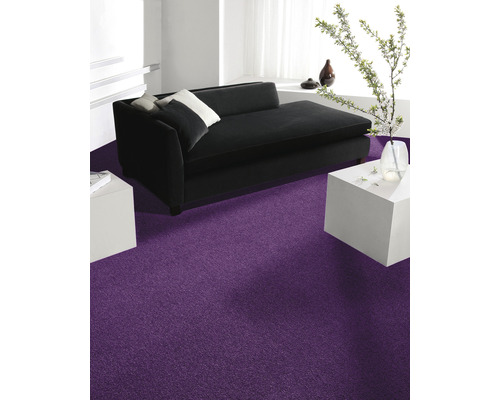 Wohnzimmer mit schwarzem Sofa, weißen Tischen und lila Teppich