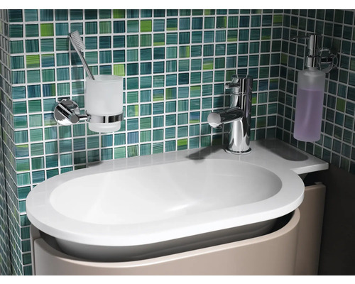 Lavabo de salle de bain avec robinet, distributeur de savon et gobelet à brosse à dents devant un mur carrelé