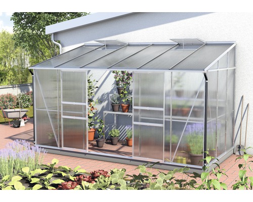 Anlehngewächshaus Vitavia Ida 7800 Hohlkammerplatten 4 mm 201x387 cm Aluminium Anlehngewächshaus mit Pflanzen in Töpfen vor einer Hauswand.