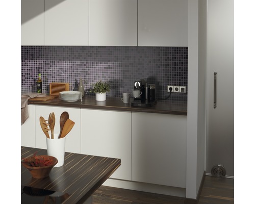 Moderne Küche mit Mosaikfliesen, Arbeitsplatte, Küchenutensilien und Kaffeemaschine.