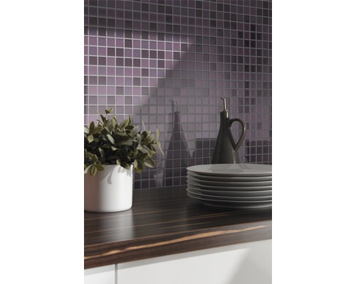 Küchenszene mit Mosaikfliesen, Arbeitsplatte, Geschirr, Pflanze und Ölflasche