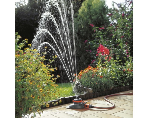 Gartenszene mit Rasensprenger, der Wasser versprüht