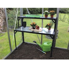 Serre avec table de culture noire à deux niveaux, arrosoir et pots de fleurs